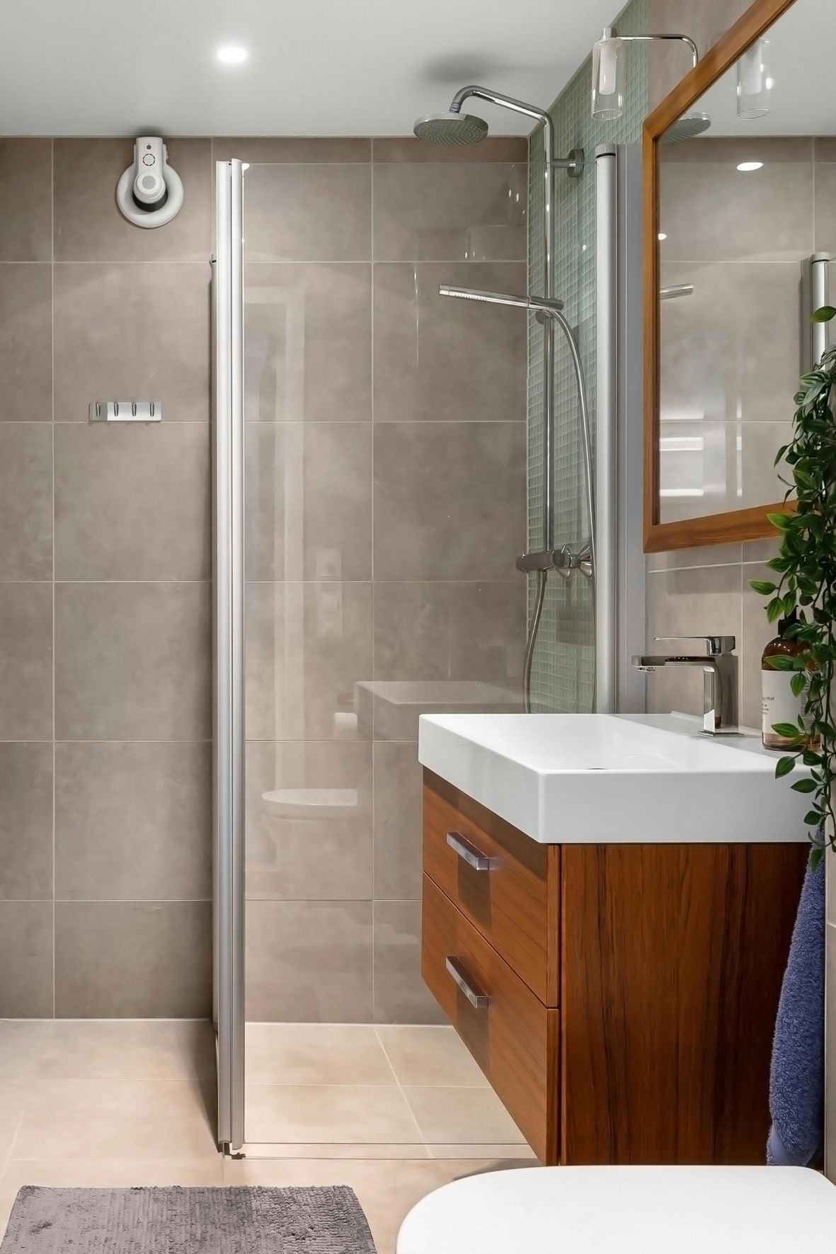 Salle de bain avec meuble lavabo suspendu en bois, vasque rectangulaire, miroir mural et douche vitrée à La Sarre