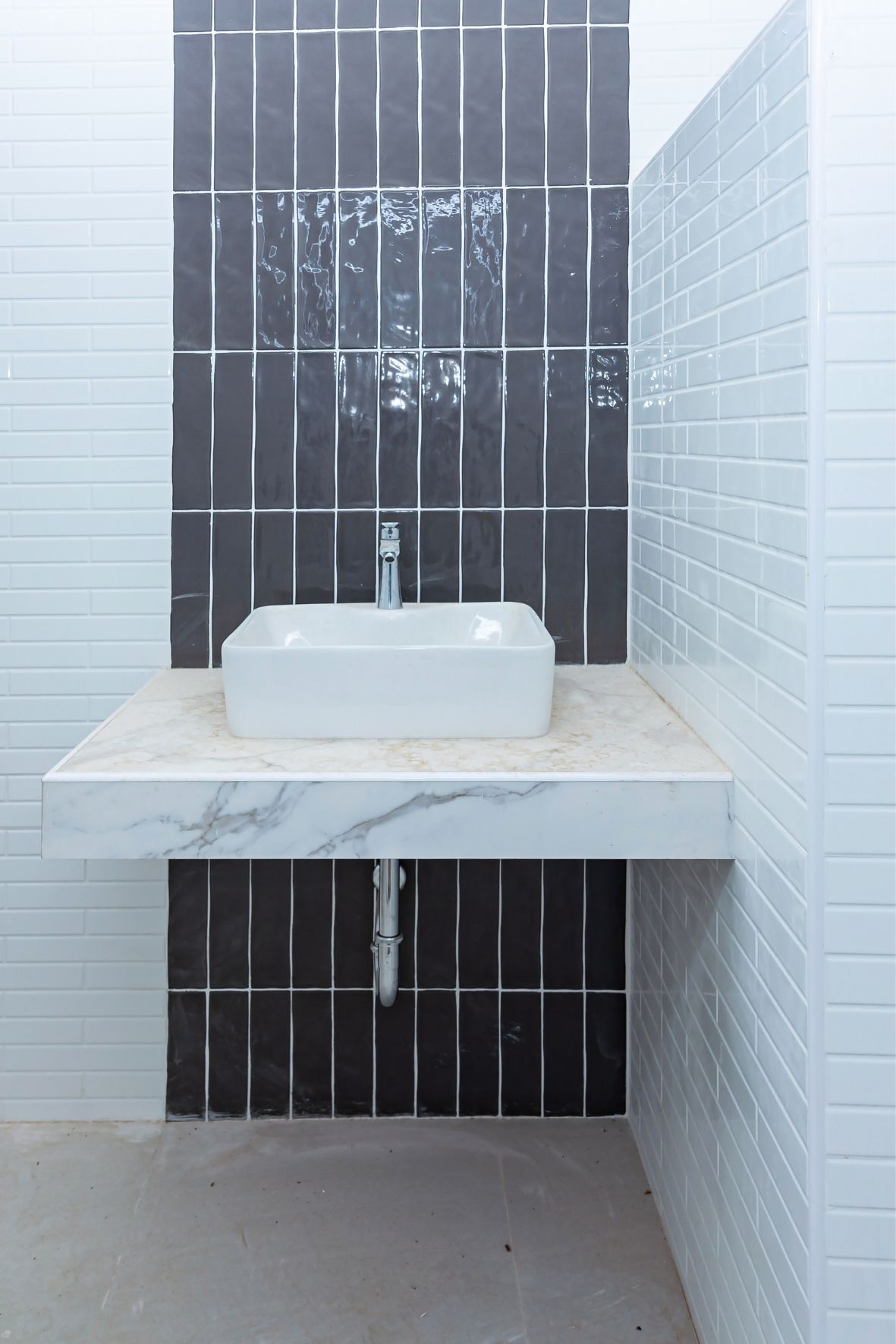 Espace lavabo avec vasque rectangulaire posée sur un comptoir clair et mur carrelé à motifs contrastés à Saint-Jean-Chrysostome